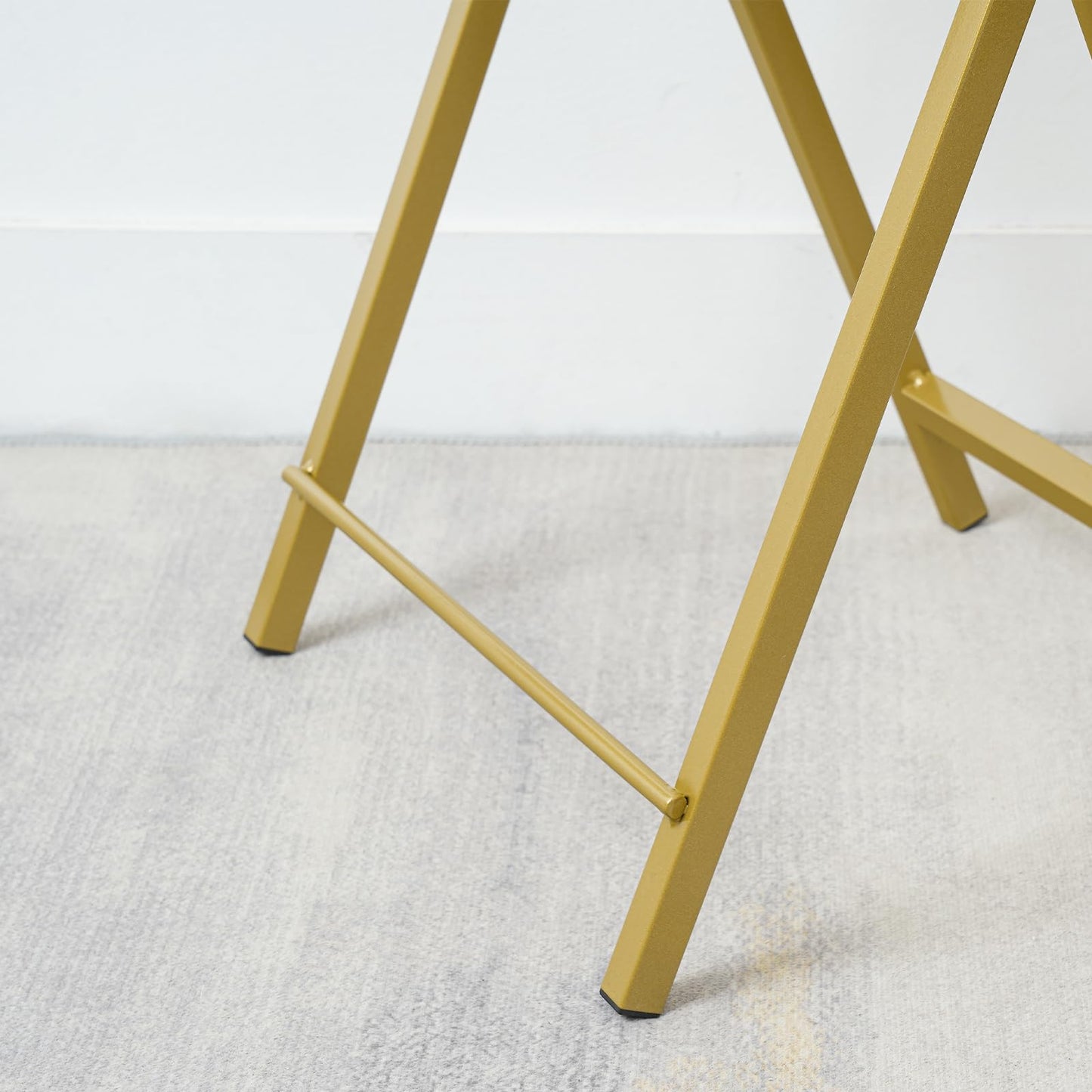 Gold metal legs of a chair on a white carpet