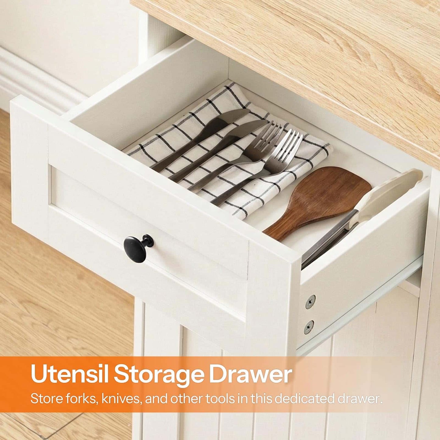 Open white utensil storage drawer with cutlery and a wooden spoon on a wooden surface.