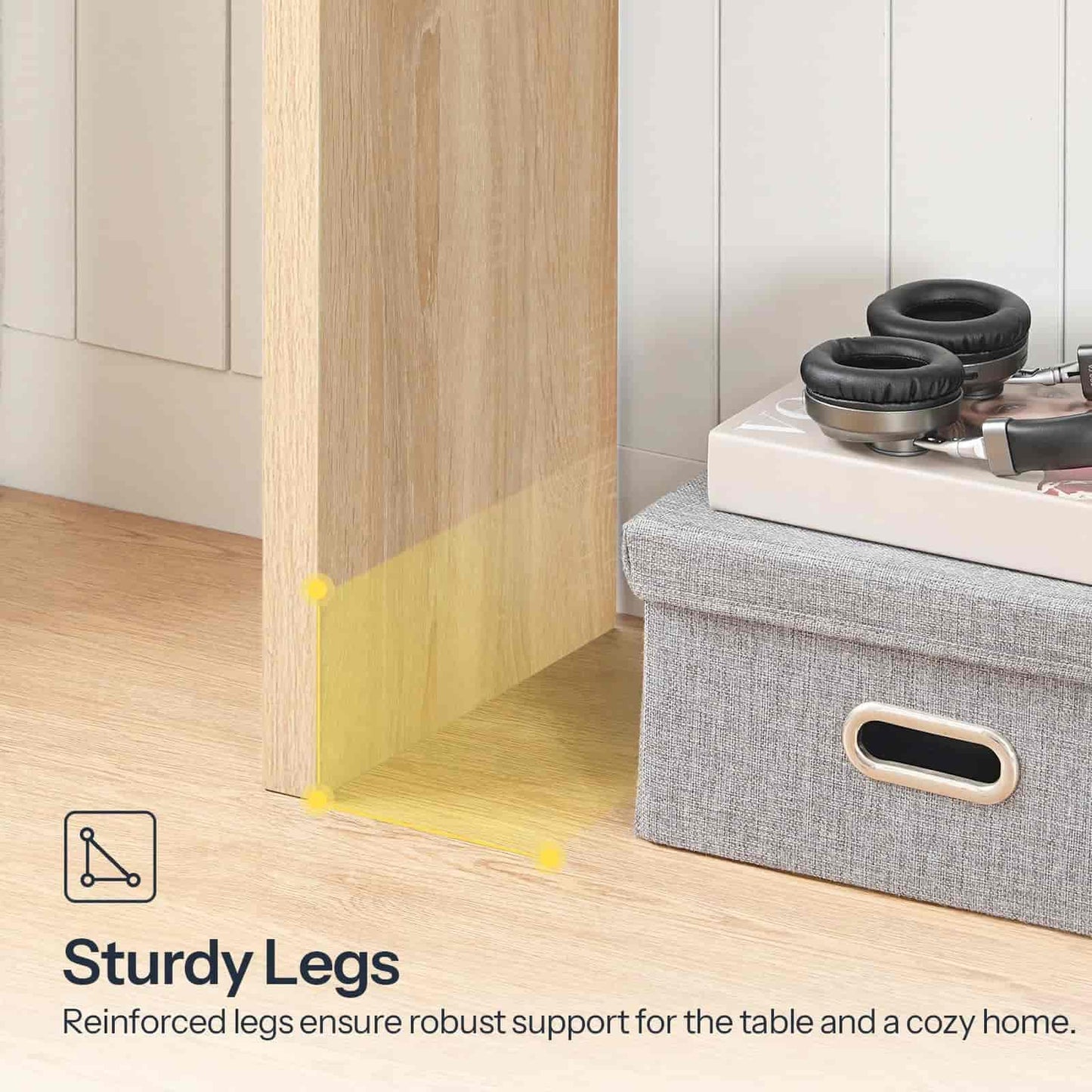 Gray storage box with headphones on a wooden floor, emphasizing sturdy legs of a table.