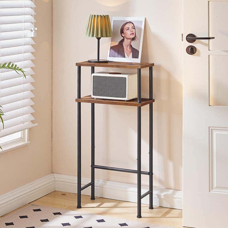 Tall narrow wooden shelf with a lamp and photo frame against a beige wall.