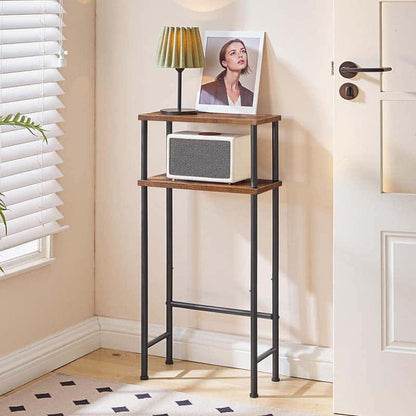 Tall narrow wooden shelf with a lamp and photo frame against a beige wall.