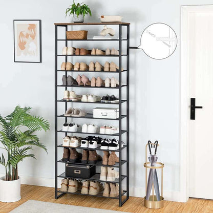 Tall black shoe rack with various shoes on shelves in a room with plants and a door.