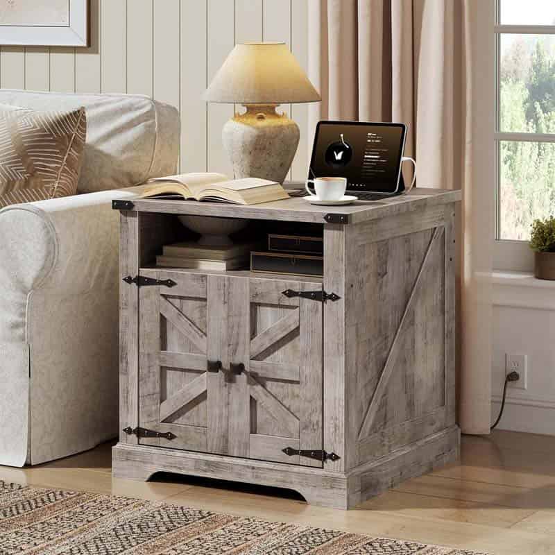 Wooden side table with a laptop, lamp, and books next to a sofa in a living room.