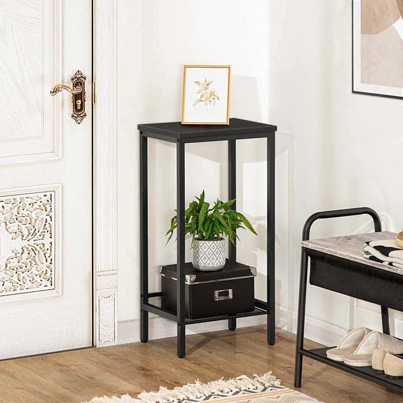 Black metal side table with a plant and decorative items in a room setting.