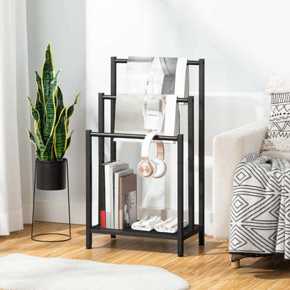 A black metal multi-tier magazine rack styled in a living room next to a sofa and a potted snake plant.