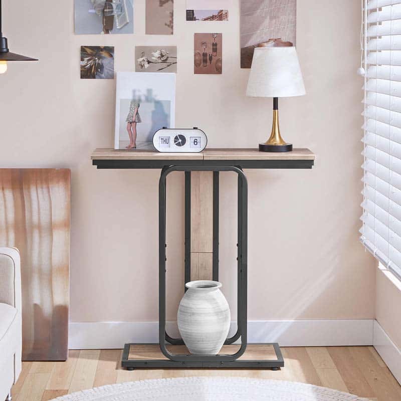 Compact hallway foyer table placed against a bedroom wall under picture frames holding a white clock.
