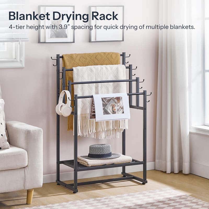 Blanket drying rack with blankets, a hat, and headphones on a stand in a room.