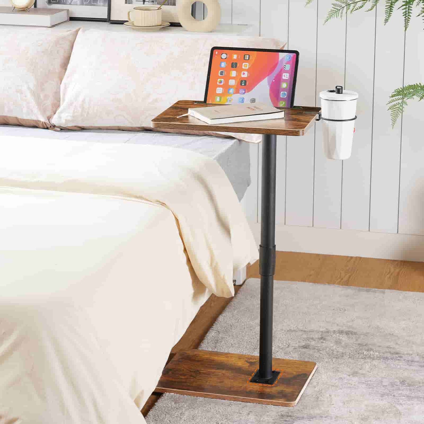 Wooden adjustable bed side table with laptop and tablet on a bed