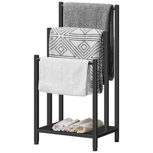 A black metal towel rack with three tiers, shown holding a gray blanket, a white and black patterned throw, a white towel, and three rolled towels on the bottom shelf, set against a plain white background.