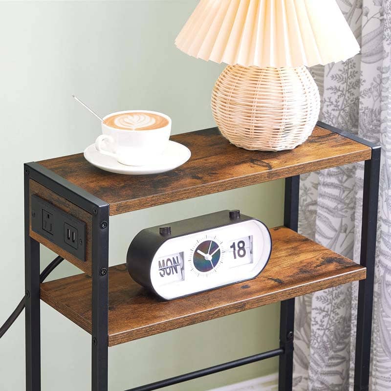 Wooden side table with clock, lamp, and cup of coffee against a light green wall.