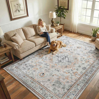 Woman reading a book on a beige sofa with a dog lying on a patterned rug in a living room.