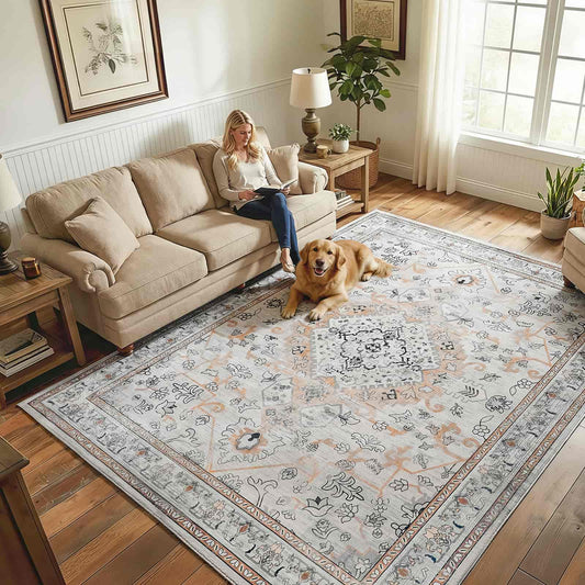 Woman reading a book on a beige sofa with a dog lying on a patterned rug in a living room.