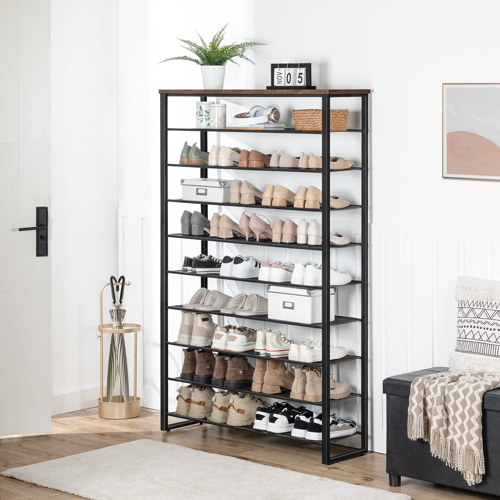 Shoe rack with multiple pairs of shoes in a room with a plant and a calendar.