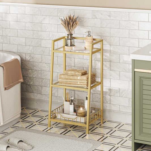 Gold metal shelf in a bathroom with towels and decorative items against a tiled wall.