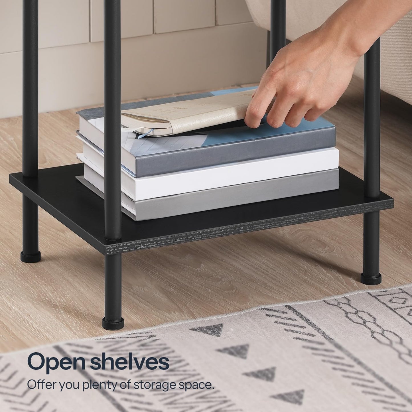 Black metal shelf with books and a hand reaching for them, on a wooden floor.