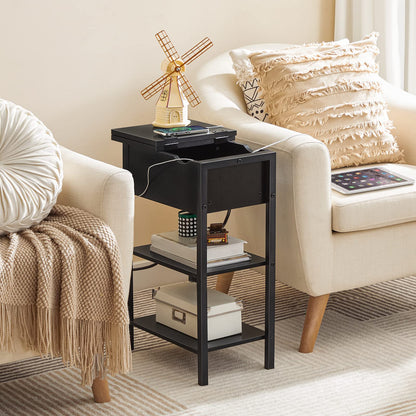 Black side table with books and a windmill decoration next to a beige sofa.
