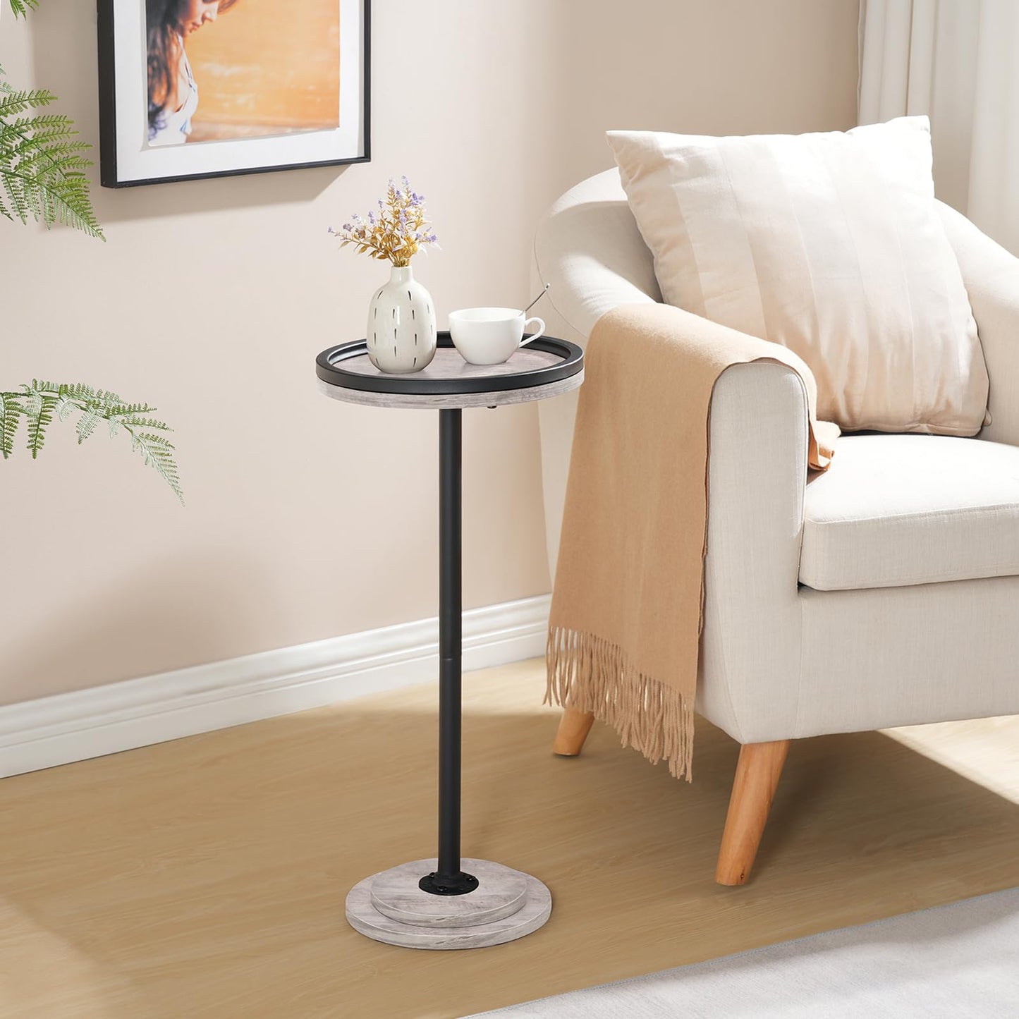 Small round side table with a cup and vase next to a beige sofa in a living room.