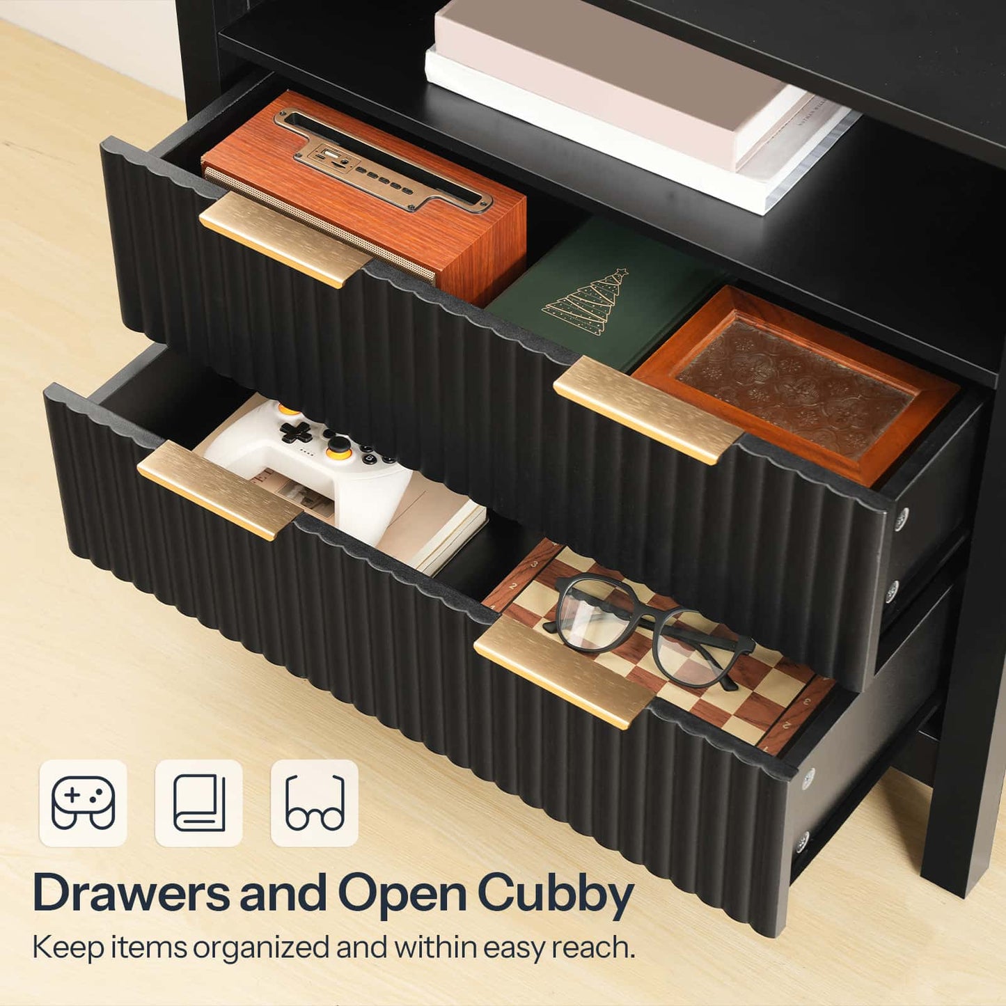 Black storage unit with open drawers and a cubby, containing items like books and a game console.