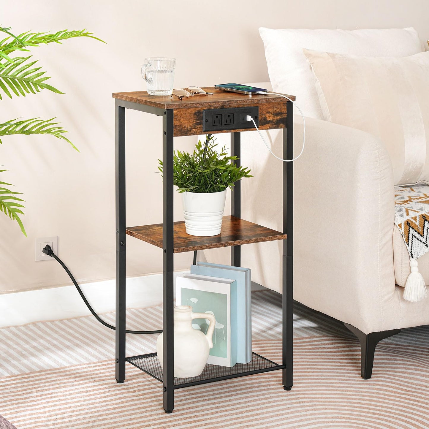 30-inch high side table with built-in charging station holding a phone and books next to a white sofa.