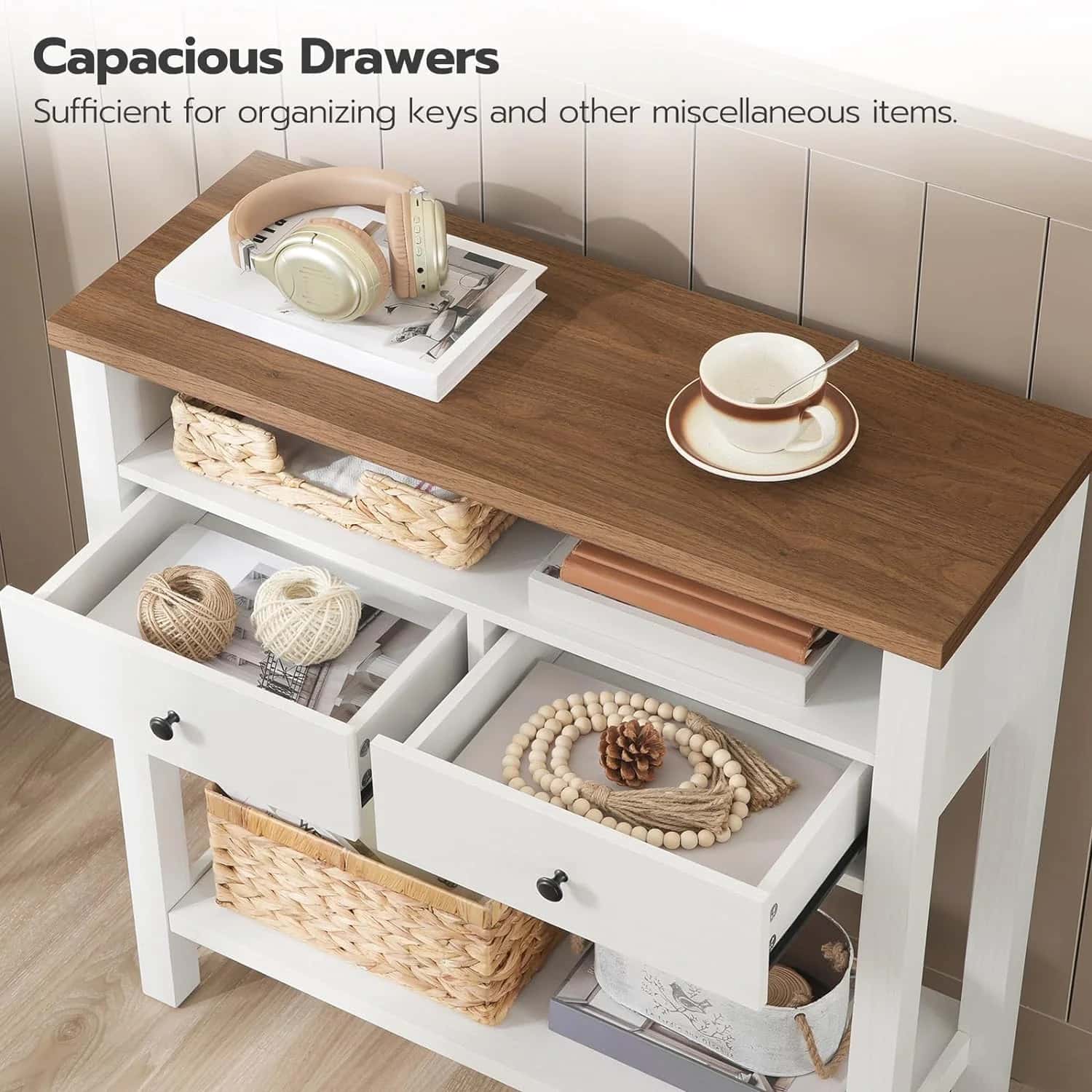 Wooden console table with open drawers containing decorative items on a wooden floor.