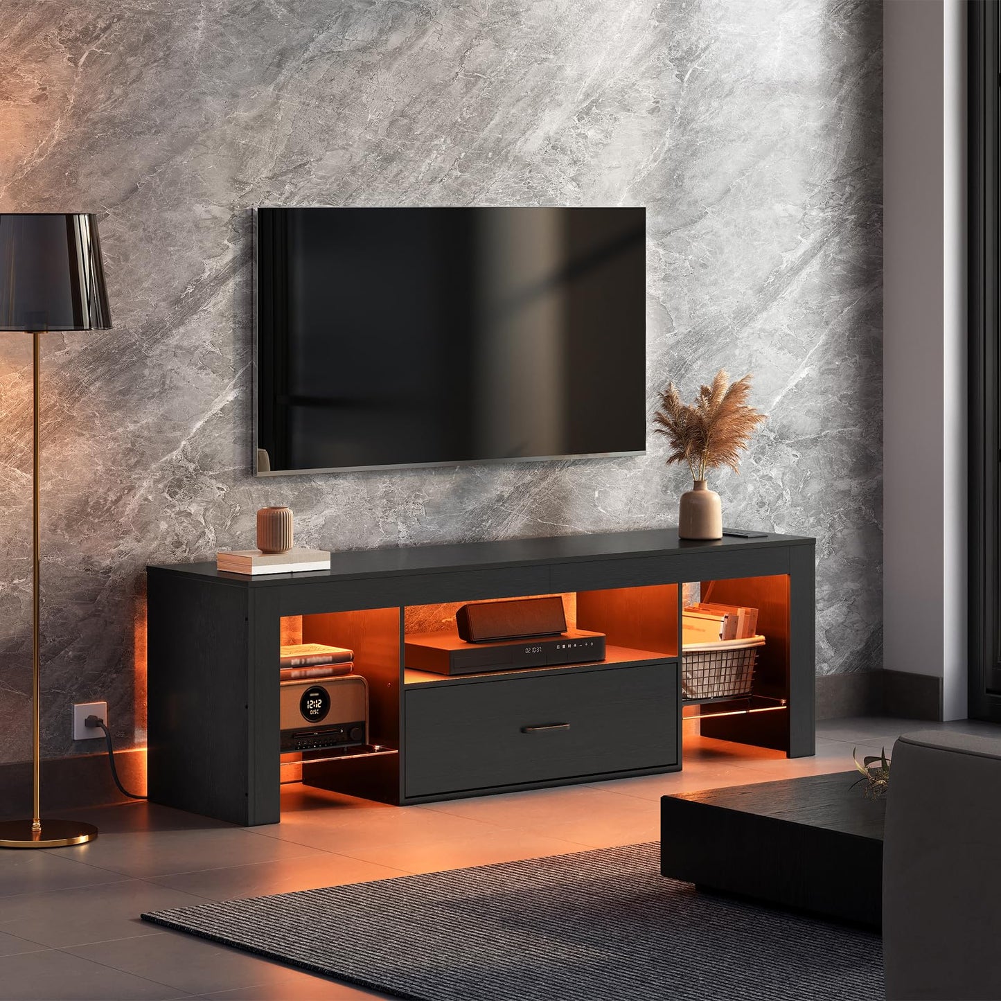 Modern living room with a black TV stand, television, and decorative items against a marble wall.