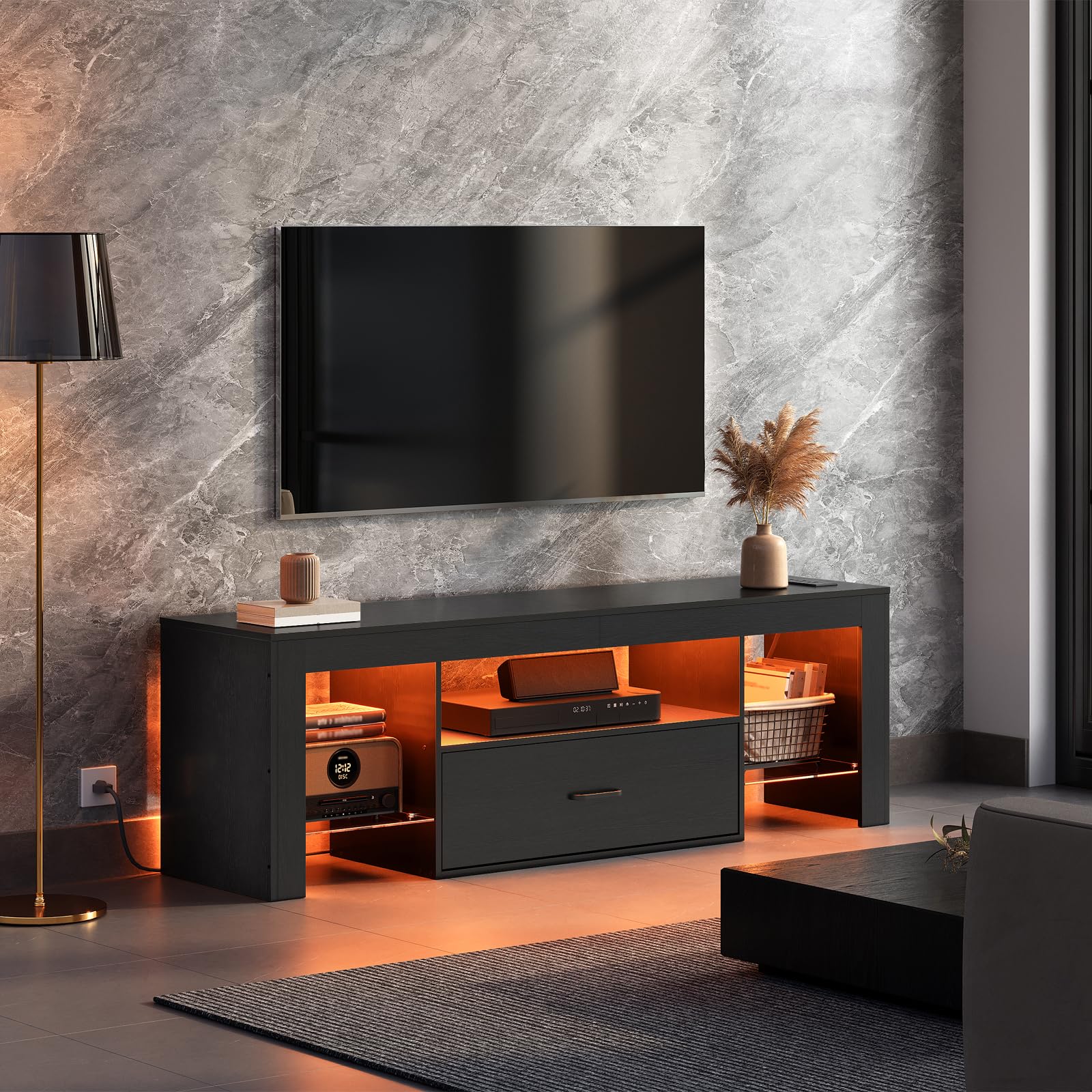 Modern living room with a black TV stand, television, and decorative items against a marble wall.