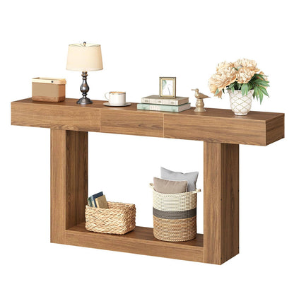 A modern console table with a warm medium-brown wood finish, styled with a lamp, books, a vase of flowers, and woven baskets on a solid white background.