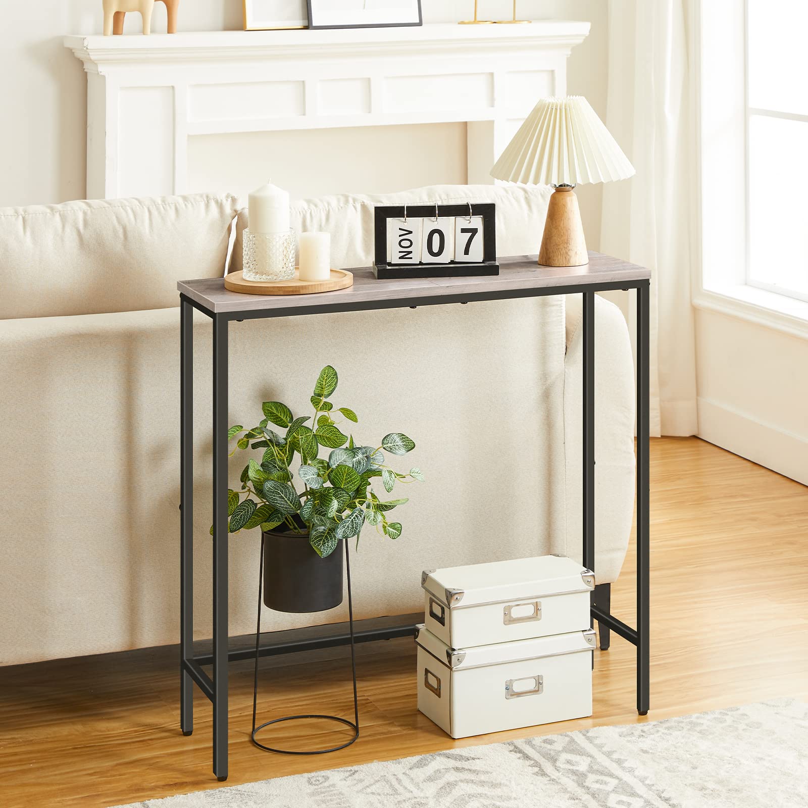 Small black metal console table with decorative items in a living room setting.