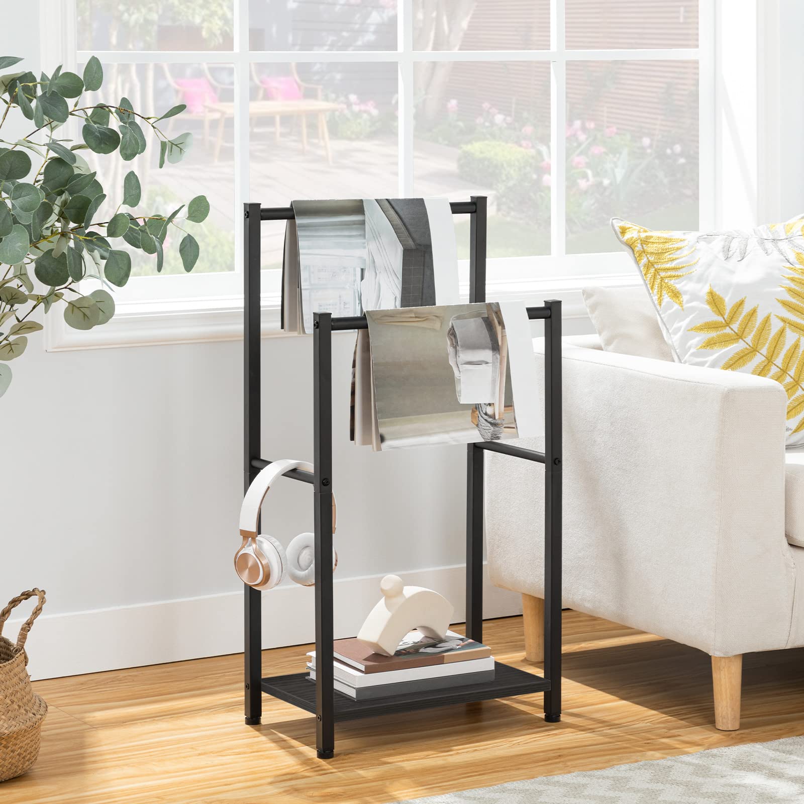 Black metal magazine rack with books and headphones in a living room setting.