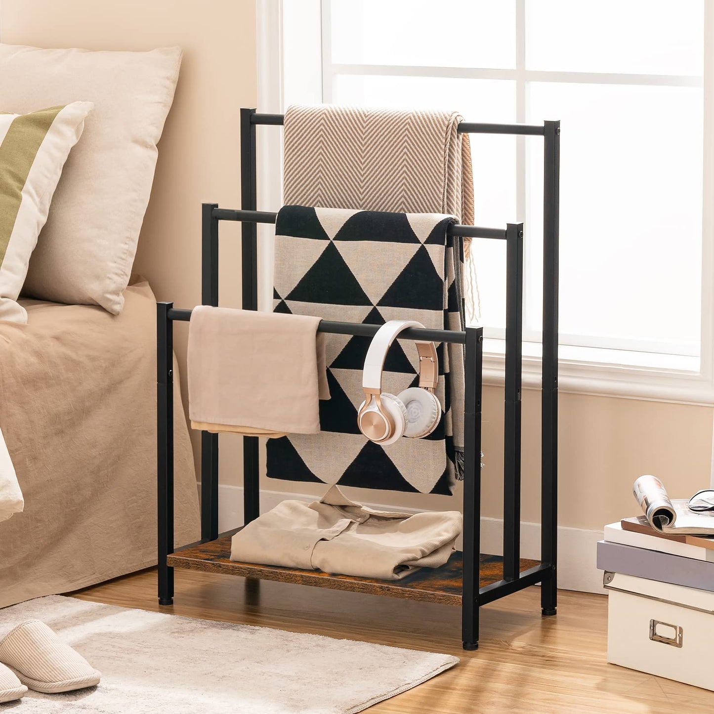Black metal blanket ladder with folded blankets and a pair of headphones in a living room setting.