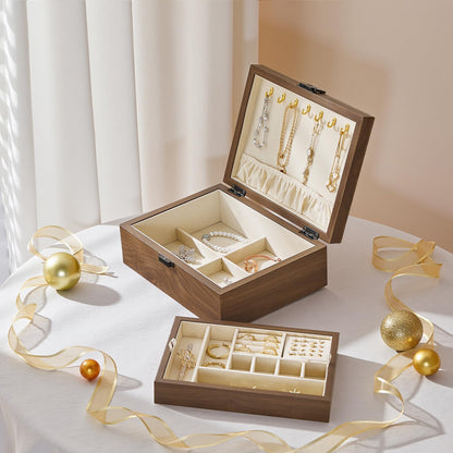 Wooden jewelry box with jewelry on a white surface with gold ribbons and ornaments.