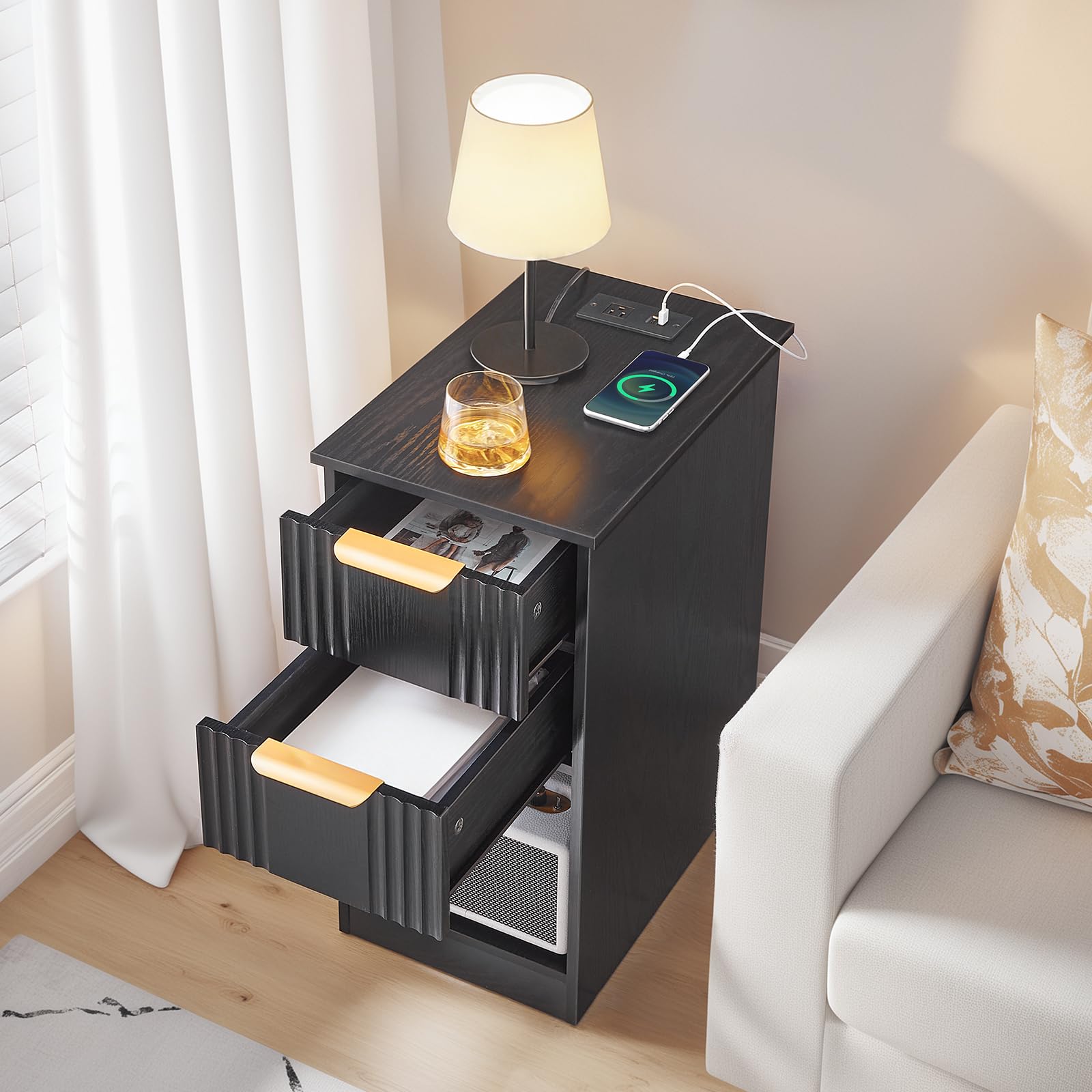 Black nightstand with lamp, phone, and glass next to a white sofa