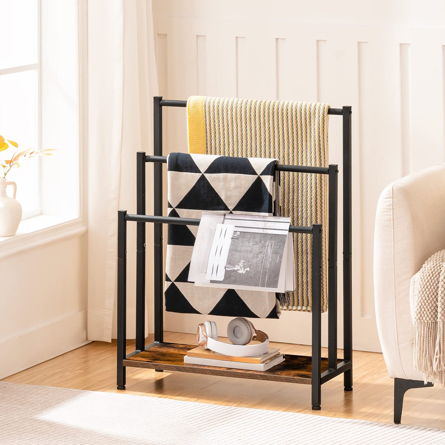 Black metal towel rack with towels and magazines in a bright room.