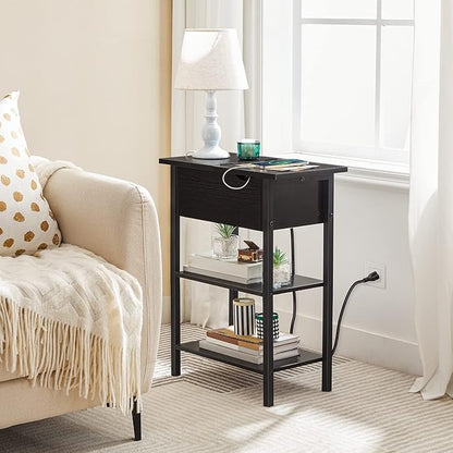 Black side table with shelves next to a beige armchair in a living room.