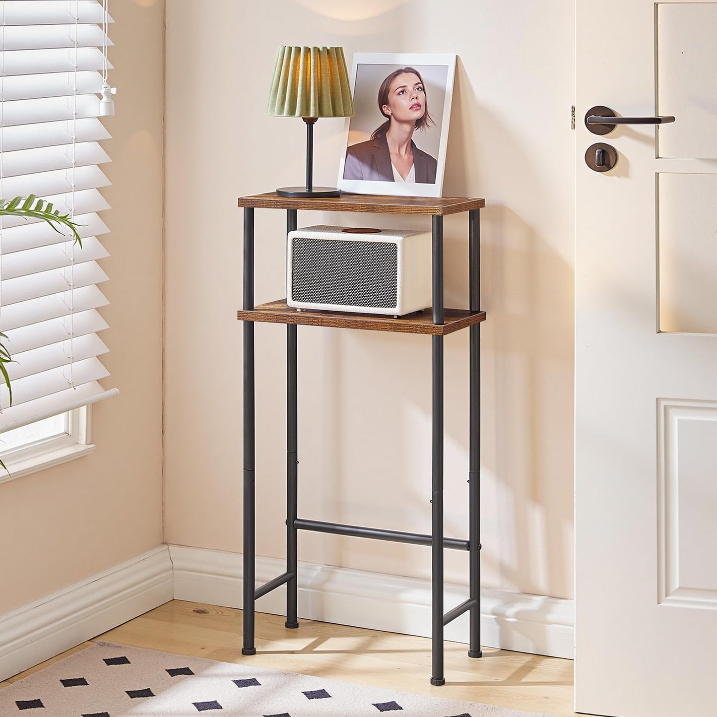 Tall narrow wooden shelf with a lamp and photo frame against a beige wall.