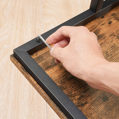 Hand using a screwdriver to assemble a wooden shelf with metal brackets.