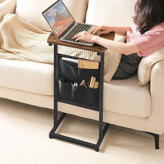 Person using a laptop on a black side table with pockets in a living room setting.