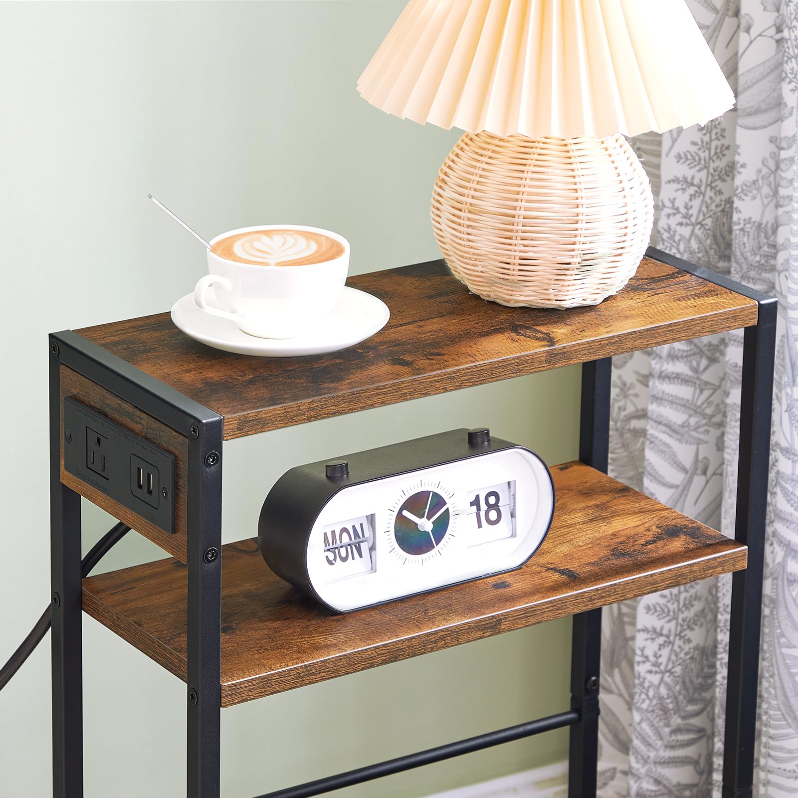 Wooden side table with clock, lamp, and cup of coffee against a light green wall.