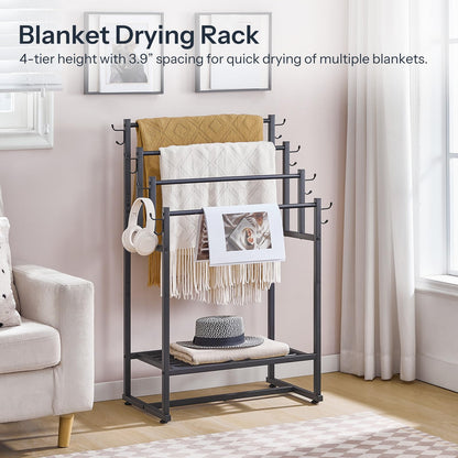 Blanket drying rack with blankets, a hat, and headphones on a stand in a room.