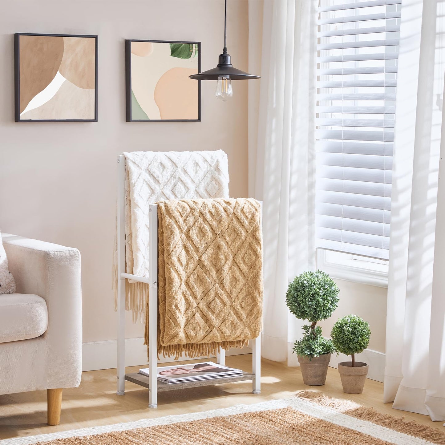 Living room with a blanket ladder, beige throw blanket, and decorative plants.