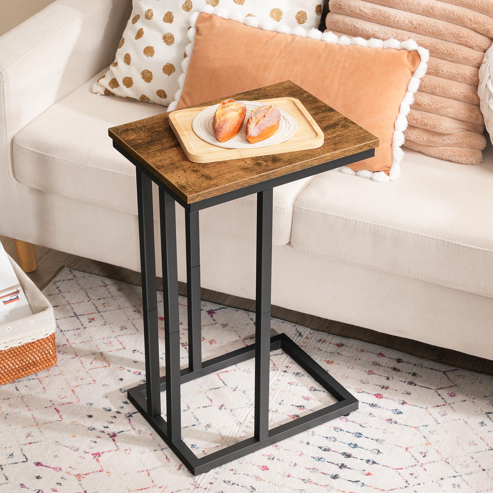 Small wooden side table with a black metal frame next to a beige sofa with decorative pillows.