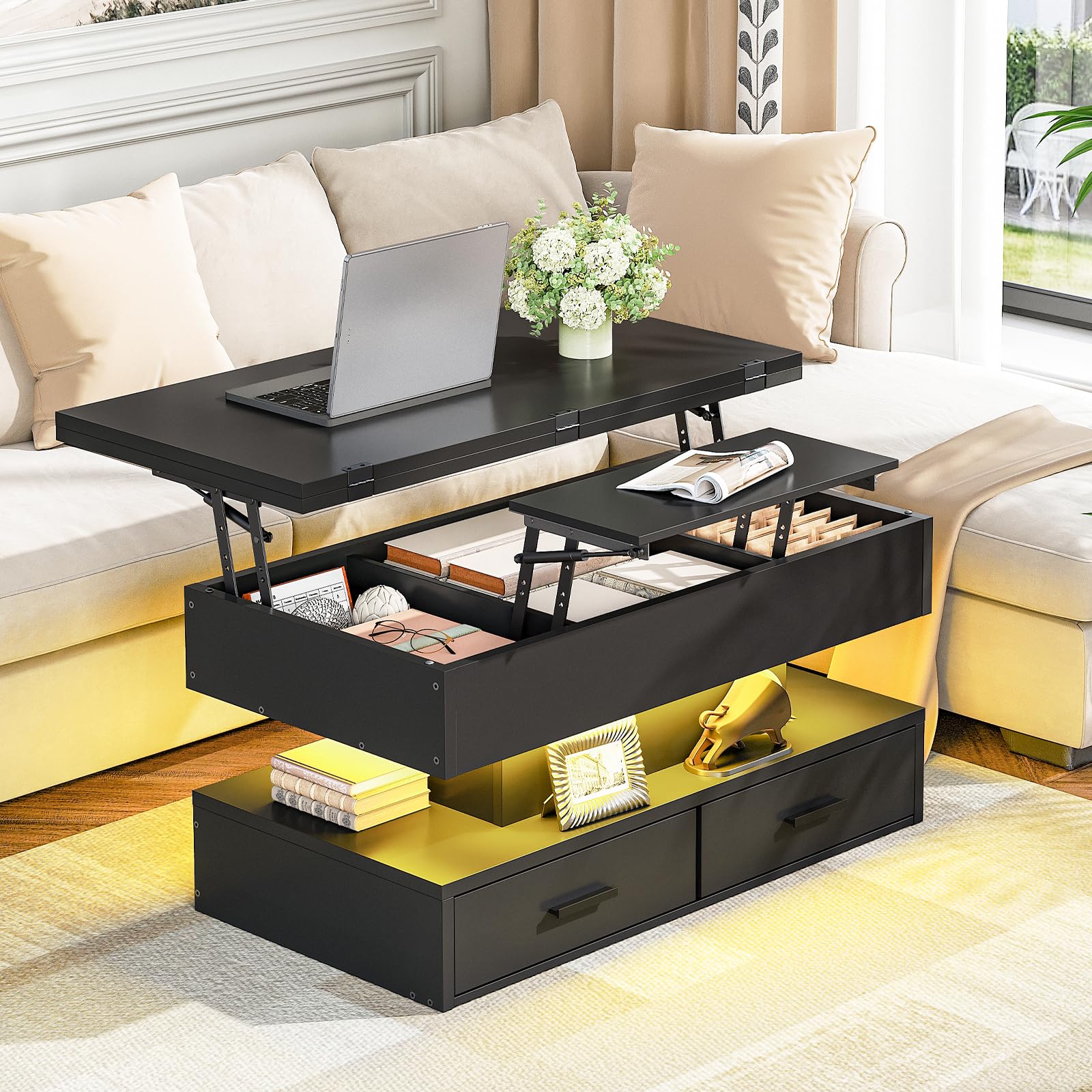 Black lift-top coffee table with laptop, flowers, and books in a living room setting.