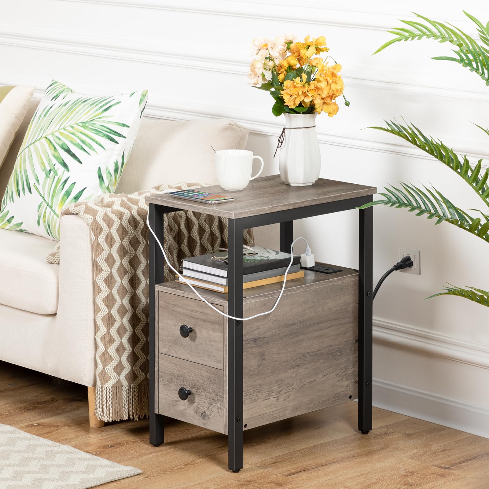 Side table with a vase of flowers, books, and a cup in a living room setting.