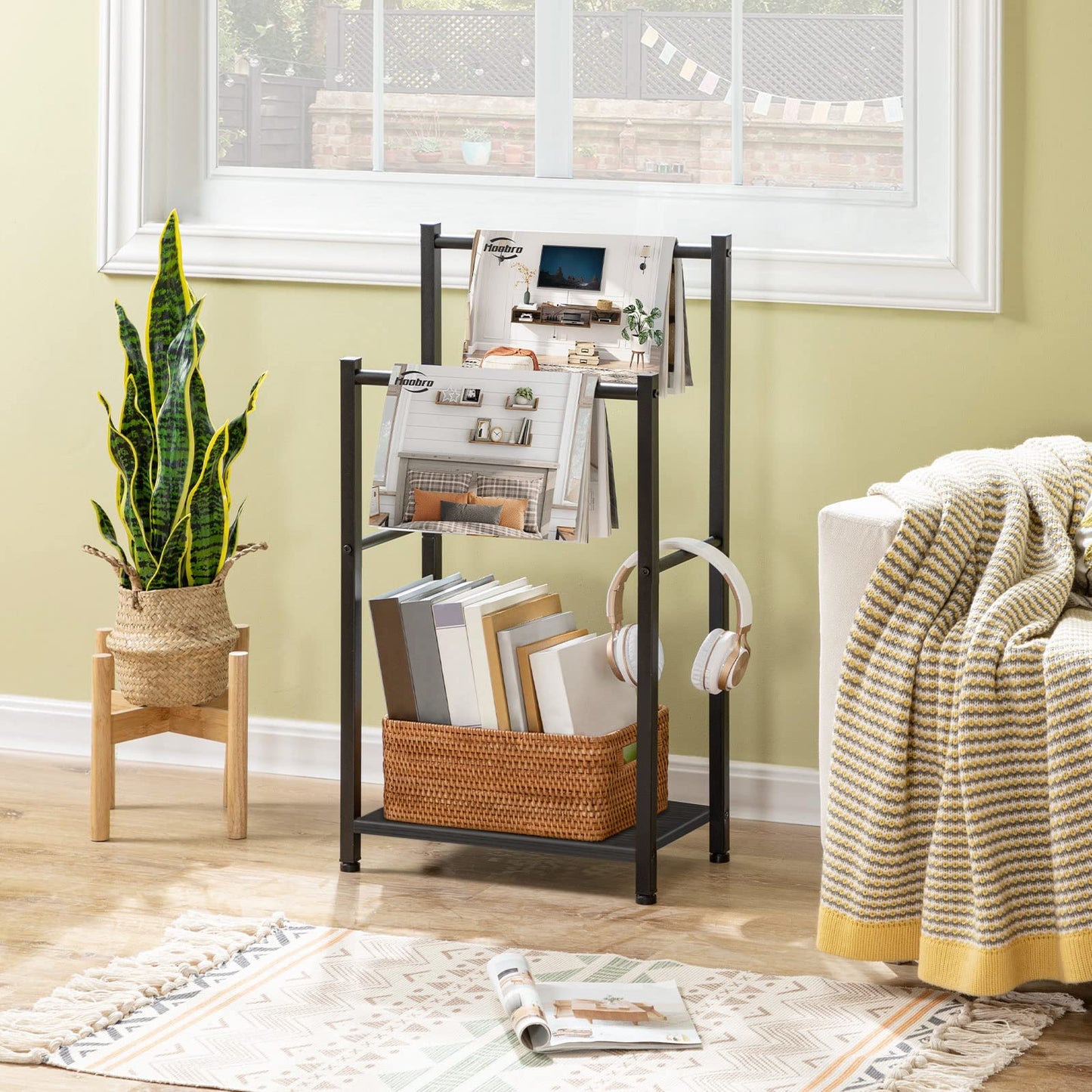 Living room with a magazine rack, plant, and books on a wooden floor.