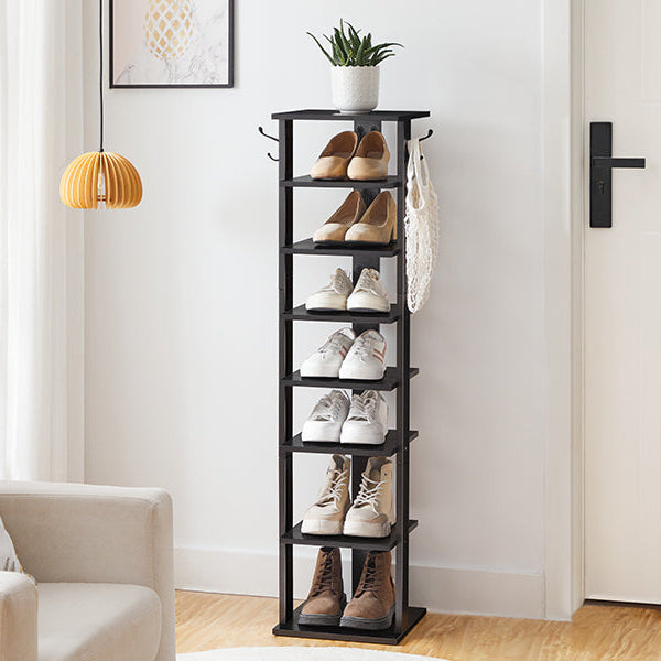 Black shoe rack with shoes on a wooden floor in a room with a couch and lamp.