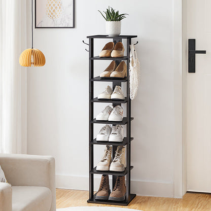 Black shoe rack with shoes on a wooden floor in a room with a couch and lamp.