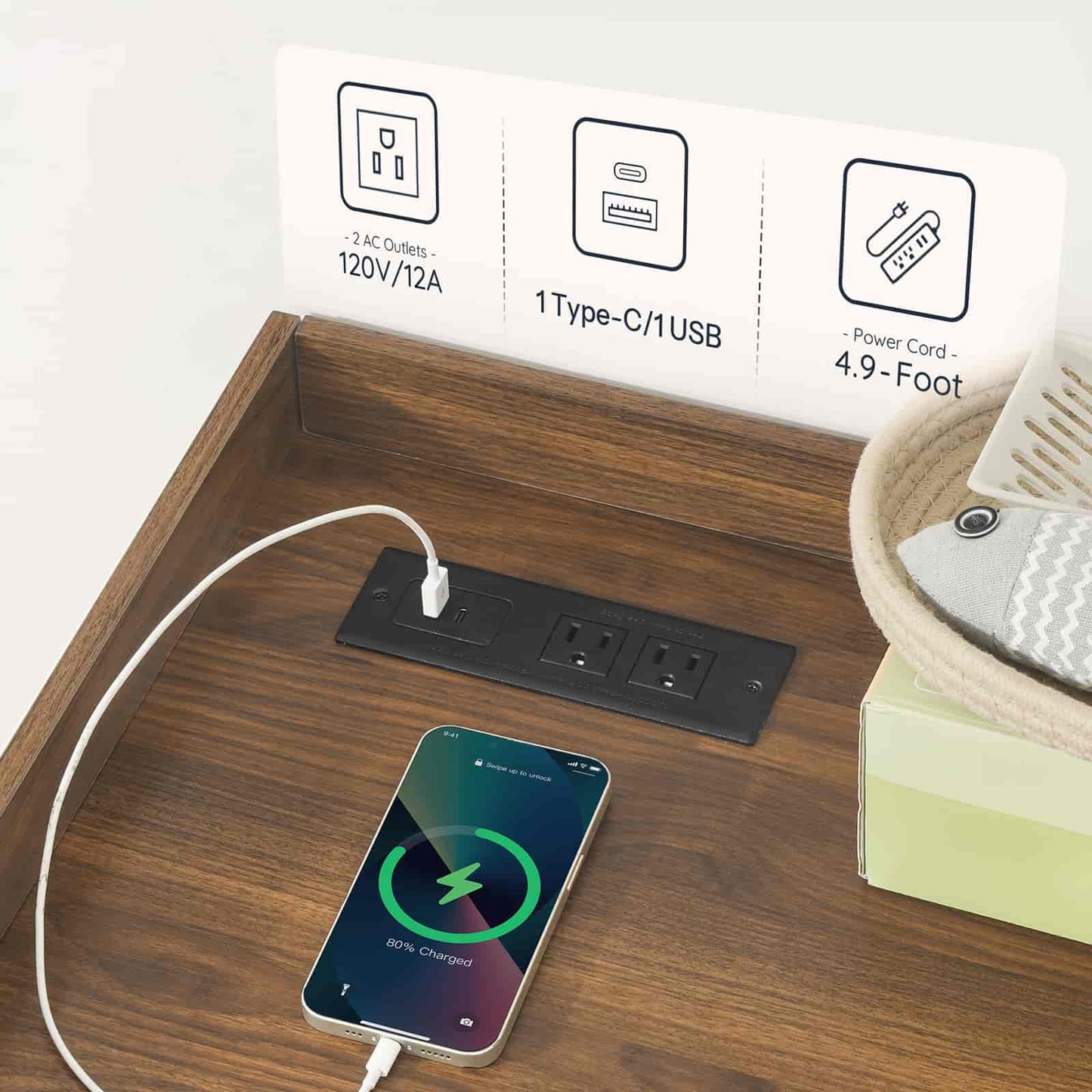 Smartphone charging on a wooden desk with power outlet and cable display in the background.