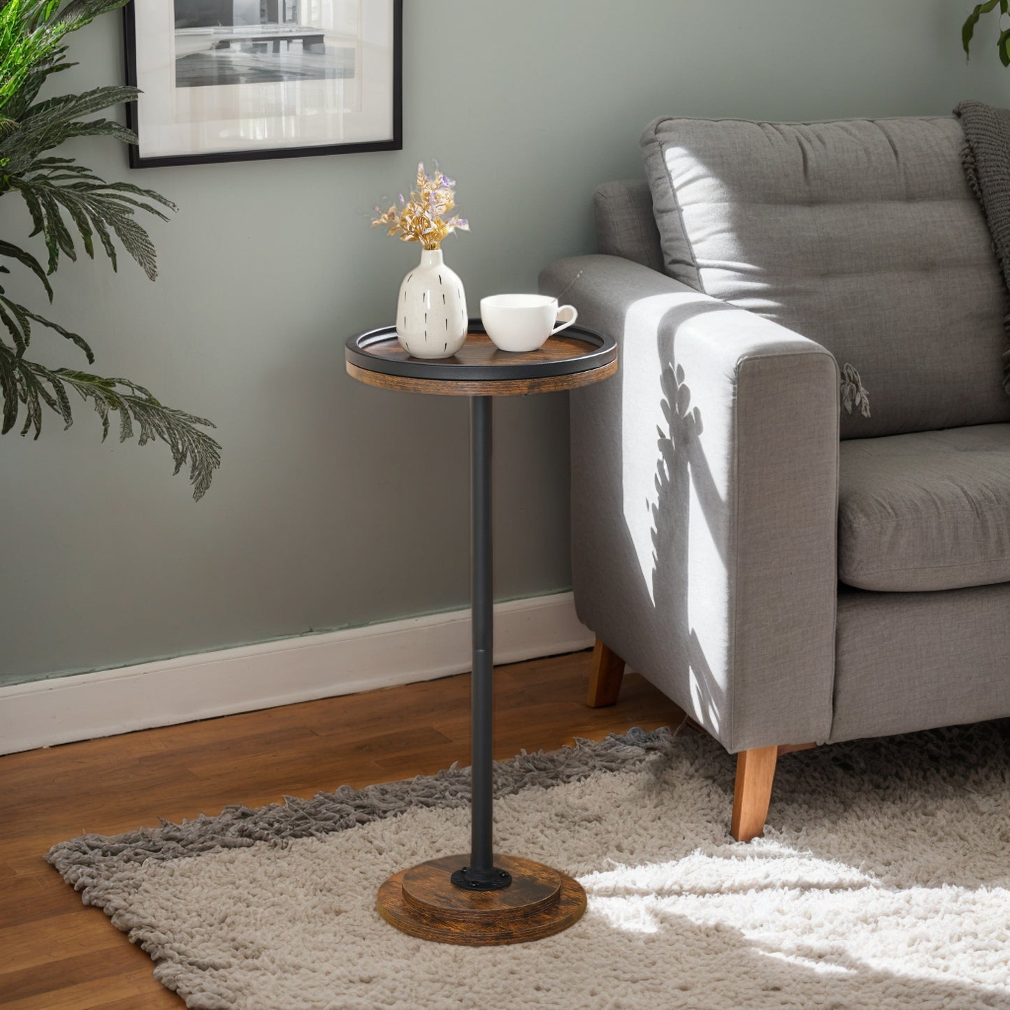 Small round wooden side table with a black metal stand next to a gray sofa in a living room.