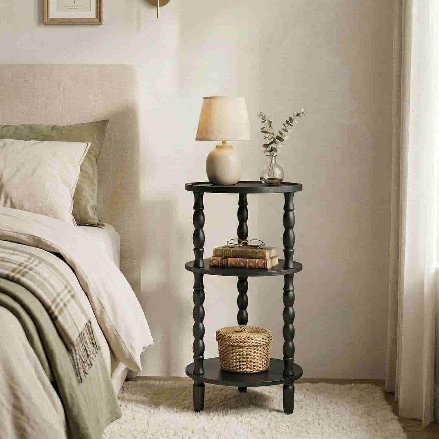 Black spiral nightstand with lamp and books next to a bed in a bedroom.