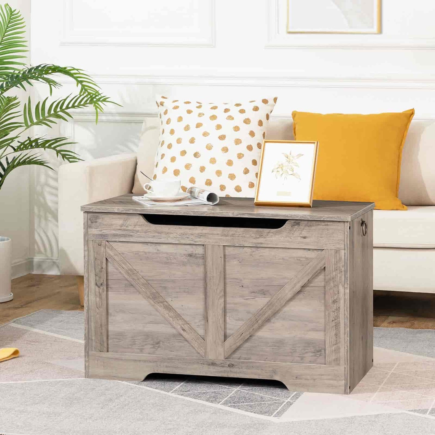 Wooden storage bench in a living room with decorative pillows and a plant.